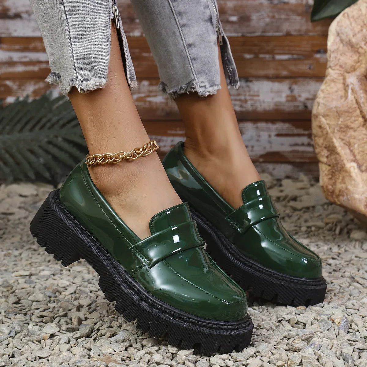 Women's black slip-on loafers with a chunky platform heel on a wooden floor