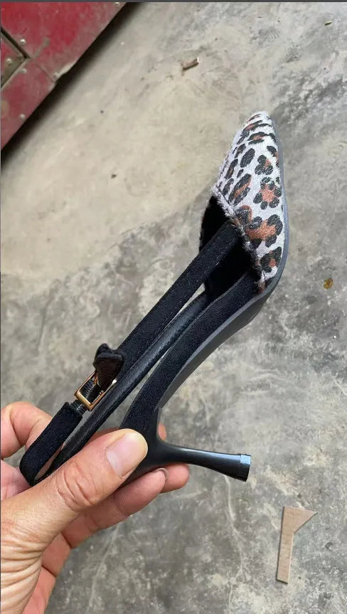 Women's leopard print suede sandals with a pointed toe and high heel on a plain background.