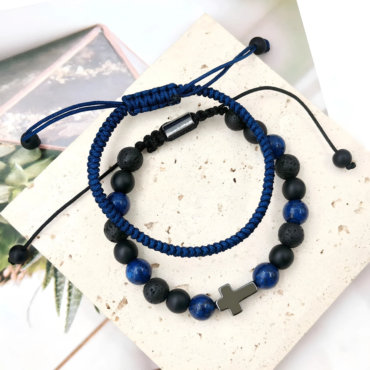 Hand-woven cross bracelet set with lapis lazuli and black matte volcanic stone beads in blue or black rope braid