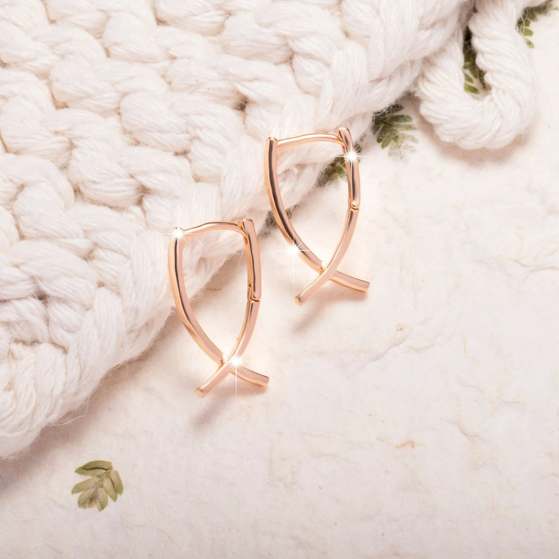 Rose gold coloured cross shaped drop earrings with contemporary light luxury styling