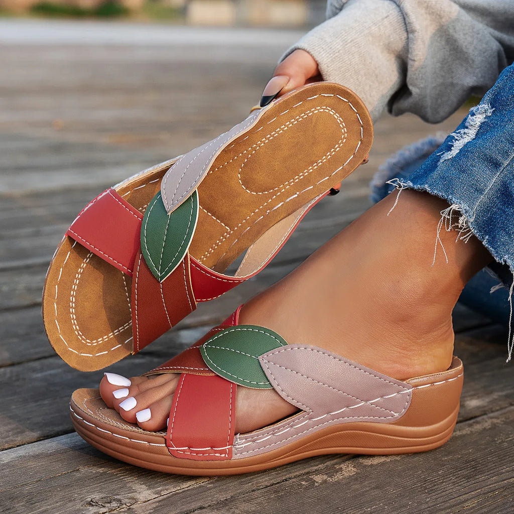 Women's black slippers with thick soles and cross-straps, showing peep-toe design.