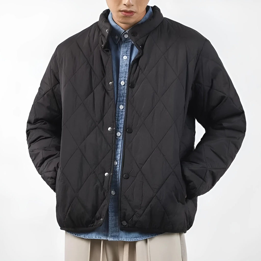 Man wearing a black diamond lattice quilted long-line winter jacket with a loose fit.