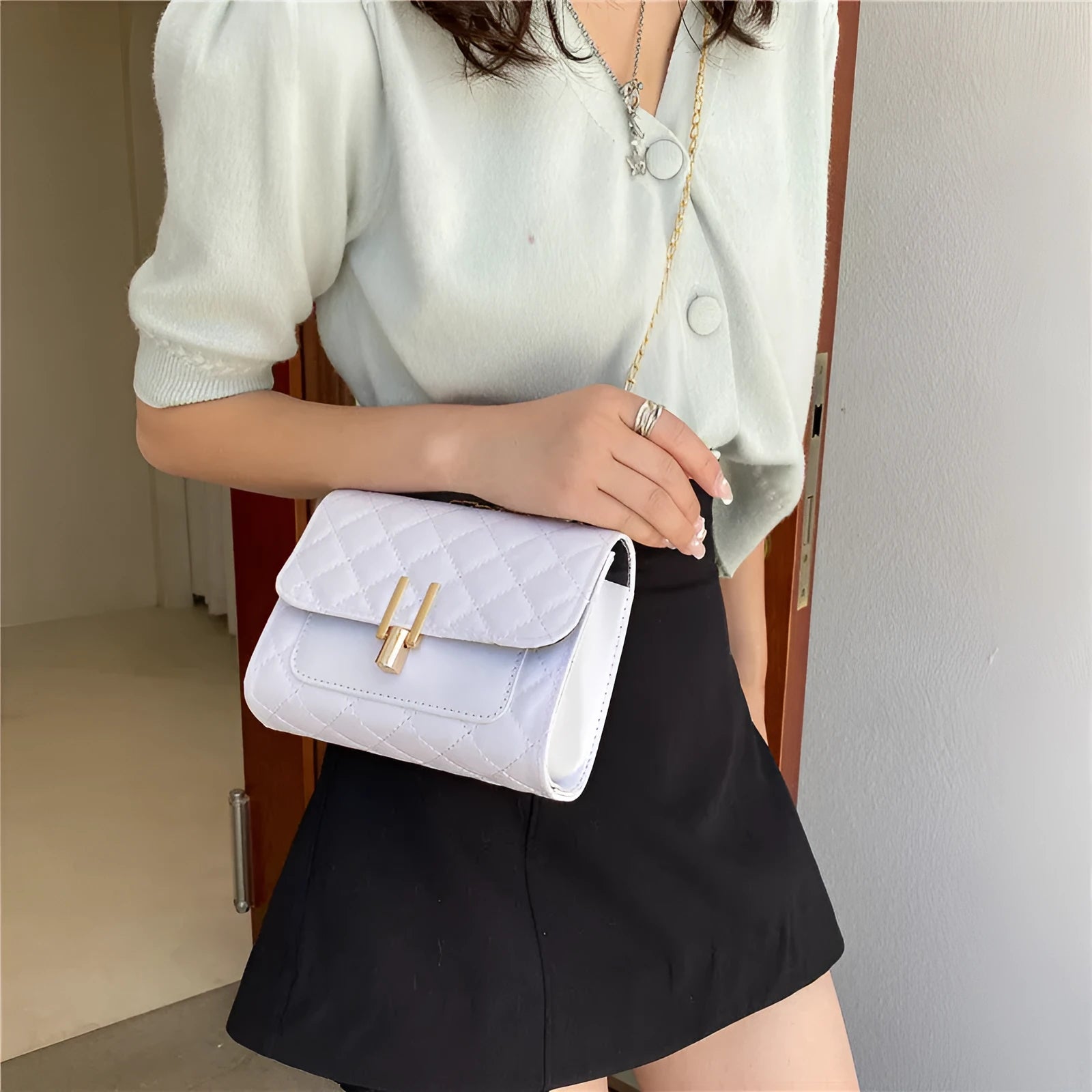 Women's diamond lattice chain crossbody bag in black with adjustable strap