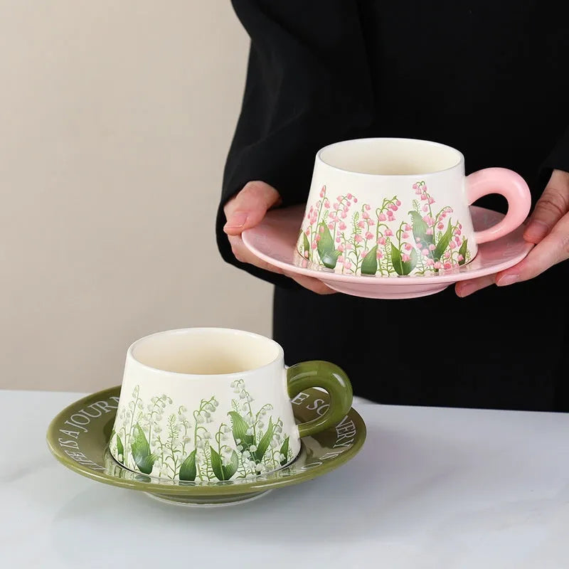 Ceramic coffee cup and saucer set for two people with stirring spoons.