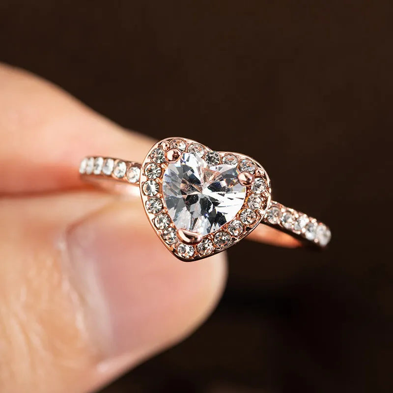 Women's heart-shaped crystal wedding ring in rose gold or silver on a white background.