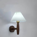 American retro-style wooden wall lamp with a fabric shade in a walnut finish on a bedroom wall.