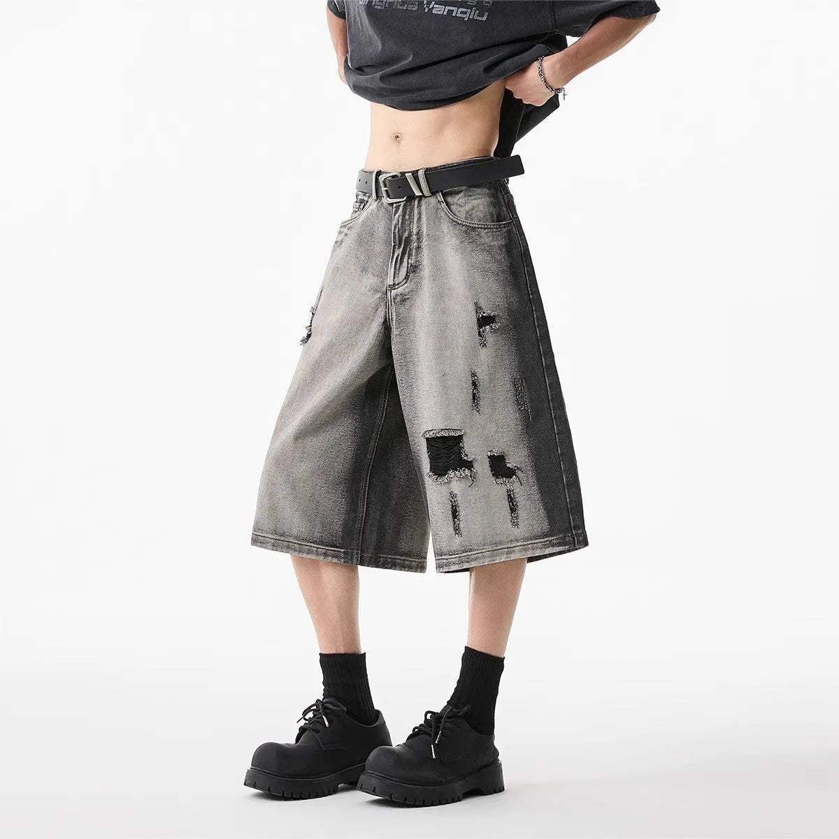 Grey loose fit denim shorts with distressed holes and a cropped length on a hanger.