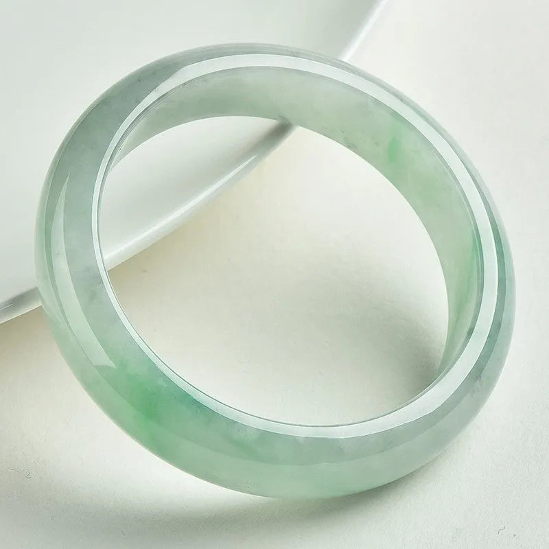 Light green jade bracelet showing natural stone colouration with size markings from 53 to 64