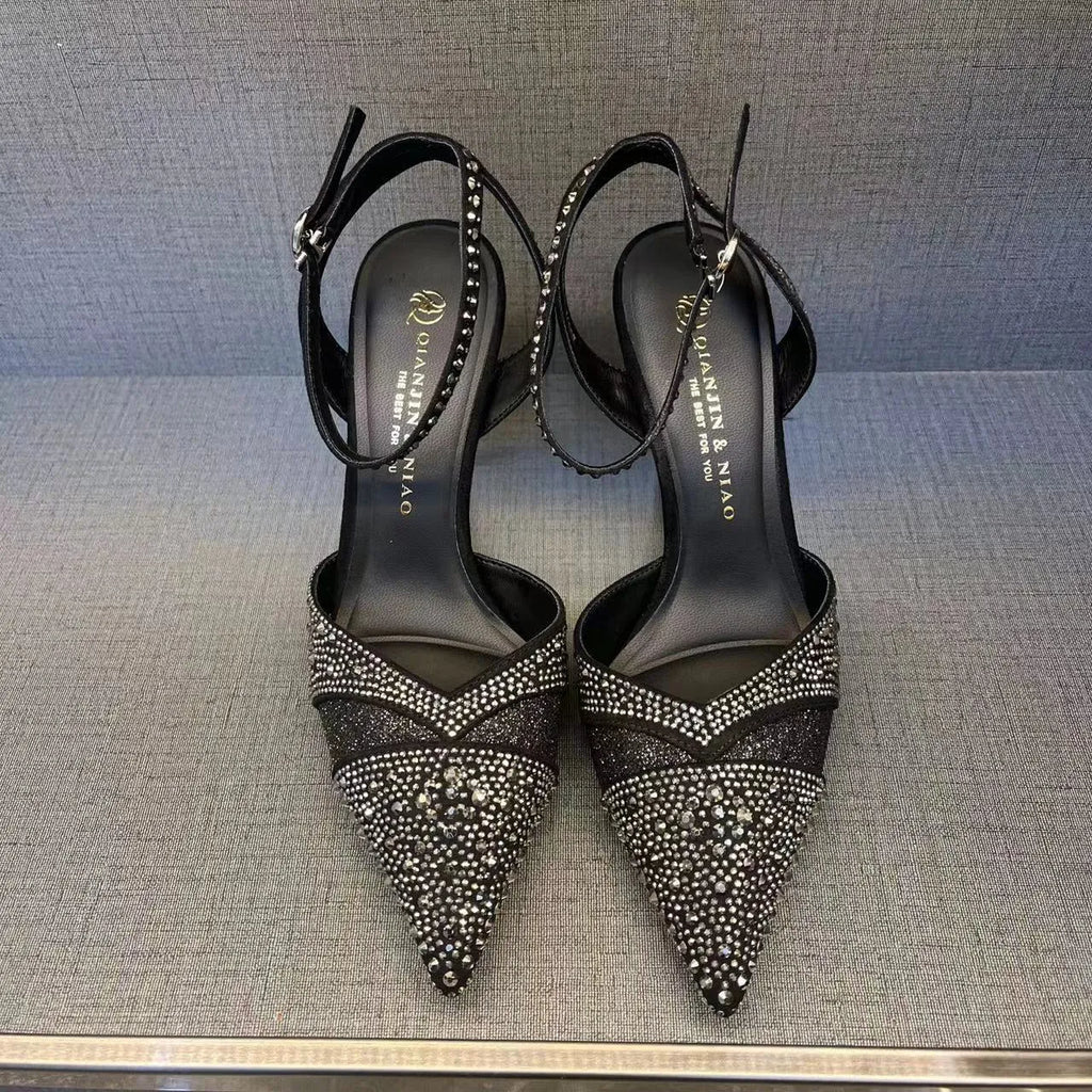 Women's black hollow high heels with red sole and stiletto heel on a plain background.