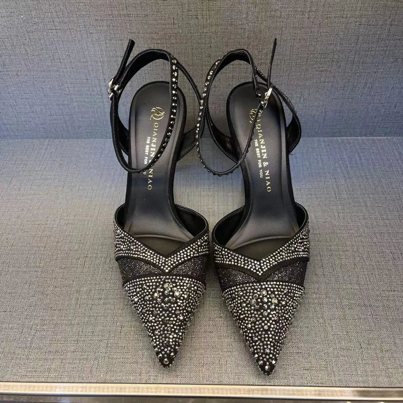 Women's black hollow high heels with red sole and stiletto heel on a plain background.