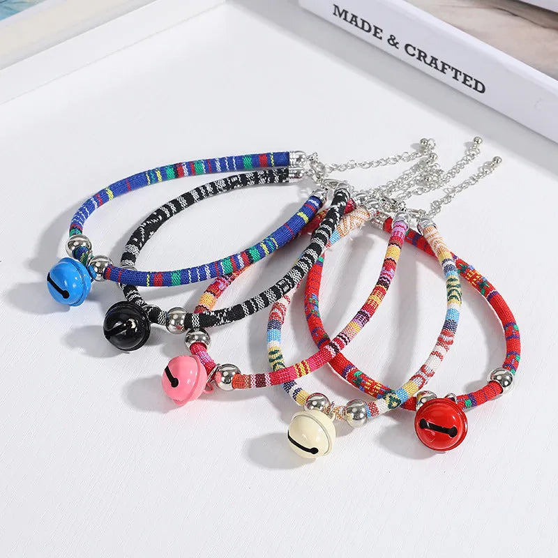 Coloured adjustable nylon pet collar with a metal buckle and brass bell in black, blue, pink, red, and white options.