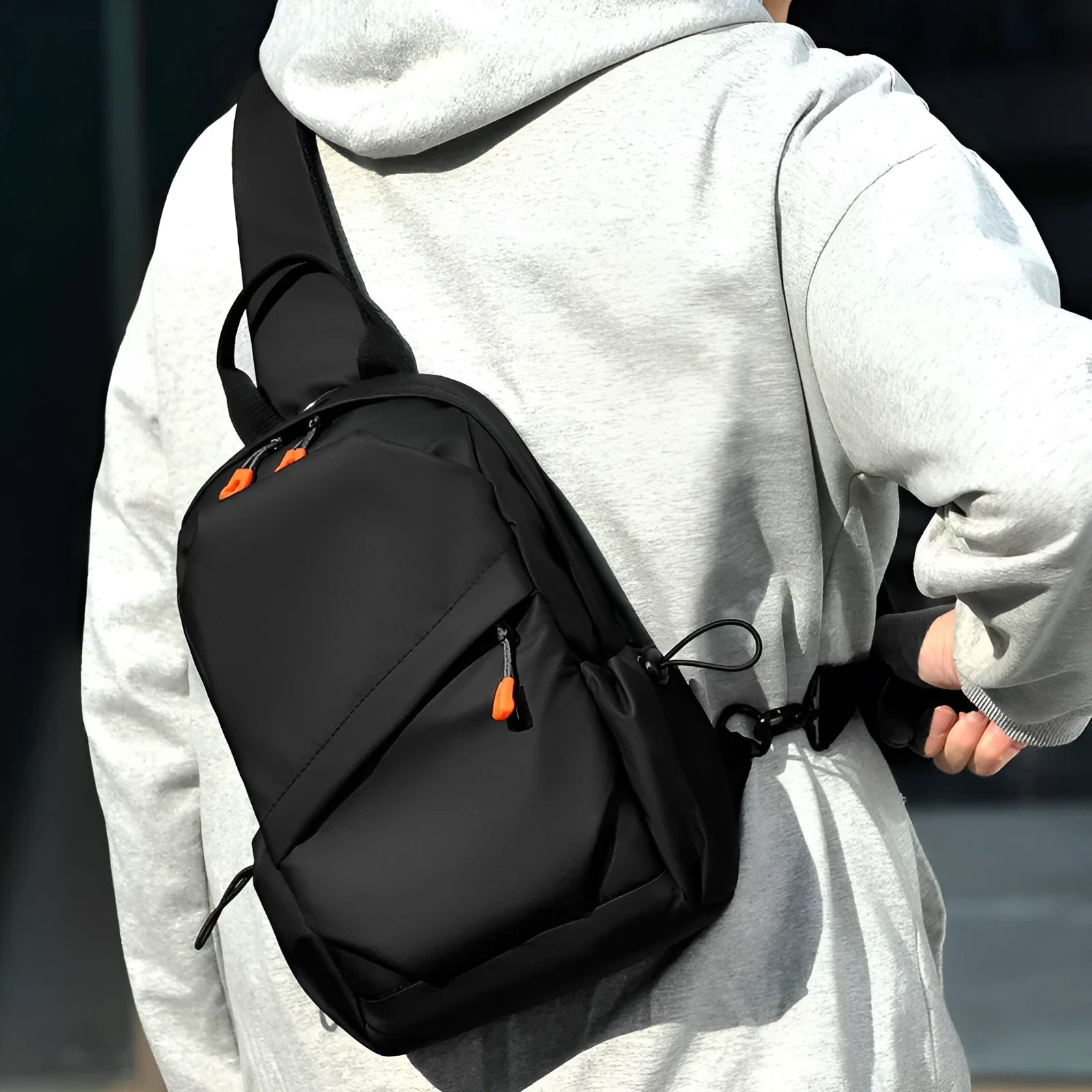 A black polyester single shoulder crossbody bag for men, shown with a model wearing it.
