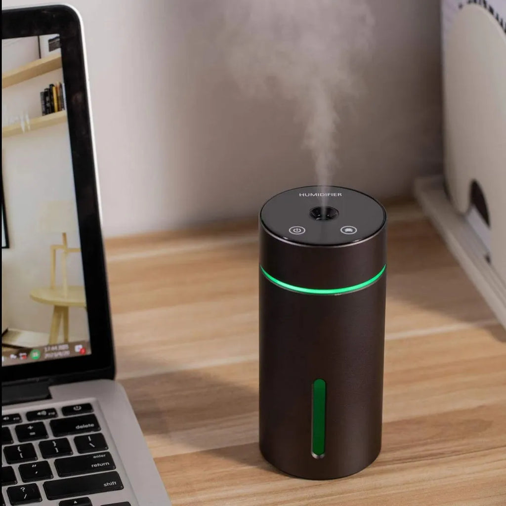 Black portable aluminium car air humidifier and essential oil diffuser with night light on a desk.