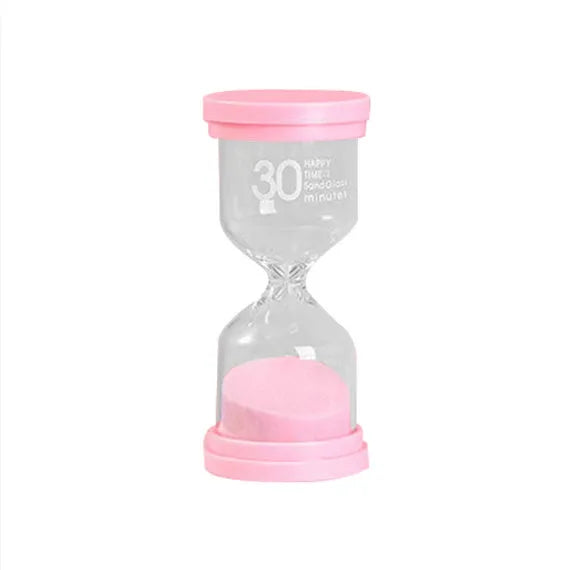Handmade glass sand timer with coloured purple sand on a wooden desk.