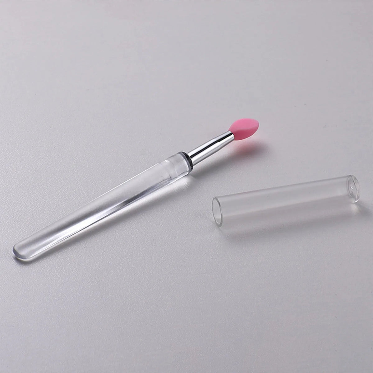 Set of reusable silicone lip brushes with protective caps in various colours on a pink background.