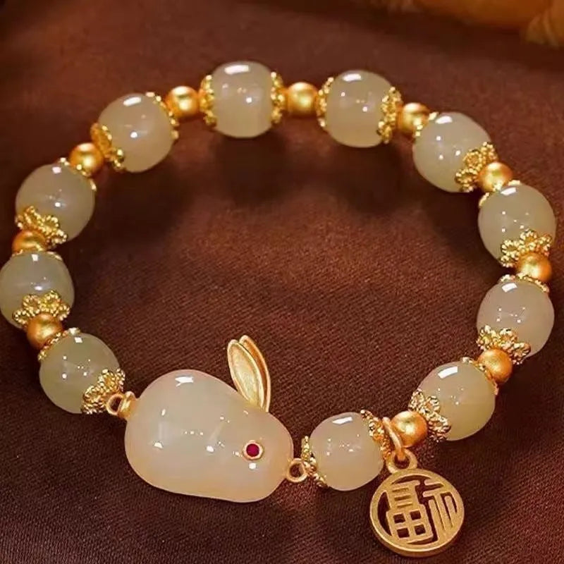 Green fu character and jade hare charm bracelet on black beaded band.