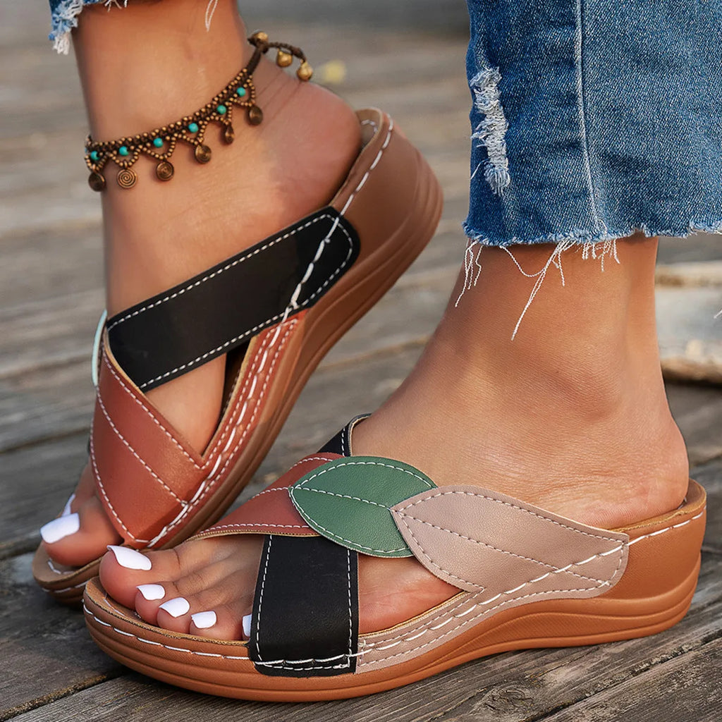 Women's black slippers with thick soles and cross-straps, showing peep-toe design.