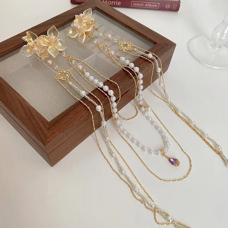 Gold women's hairpin with acrylic pearl flower, long tassels, and diamond-bead grip on a metallic pin.
