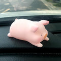 A cute resin cartoon pig figurine car dashboard decoration on a grey background.
