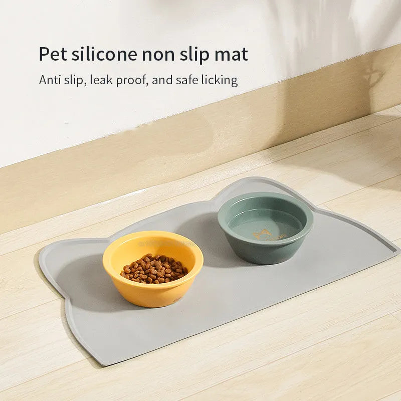 Blue silicone cat head shaped pet feeding mat placed on a wooden floor.