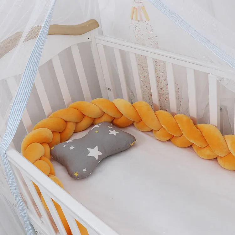 Braided knot design crib bumper in spandex velvet, shown in a light grey colour wrapped around crib slats.