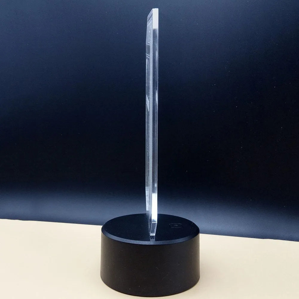 LED 3D acrylic illusion desk lamp with colourful remote control on a wooden table