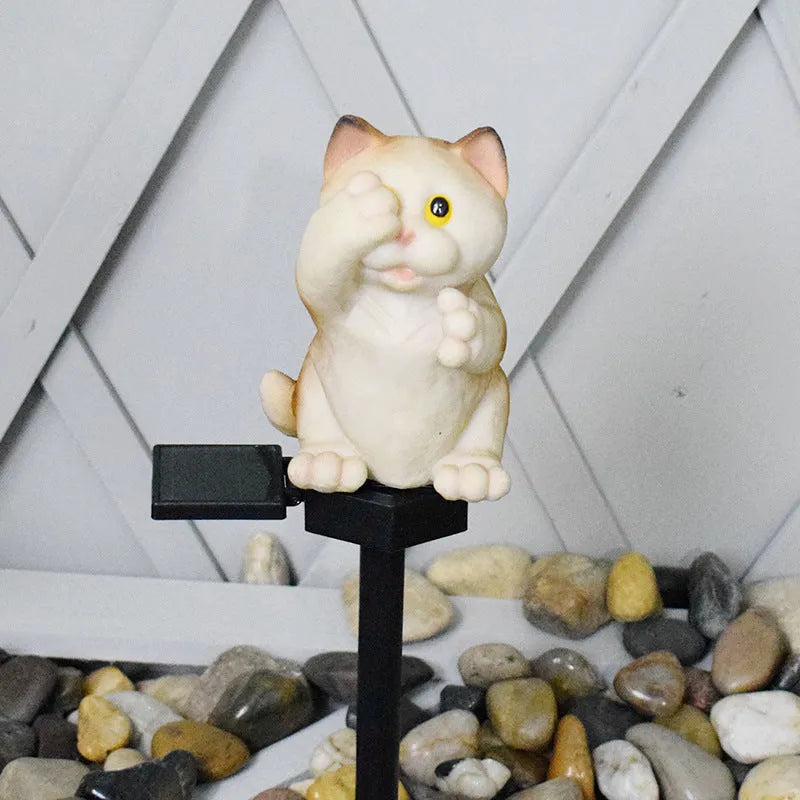 Brown resin cat-shaped solar garden light with LED on a lawn.