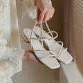 Women's flat strap open-toe Roman sandals in microfiber with a square toe, shown in a neutral colour.