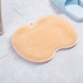 Orange silicone bristle bath brush with suction cup base on bathroom tiles.