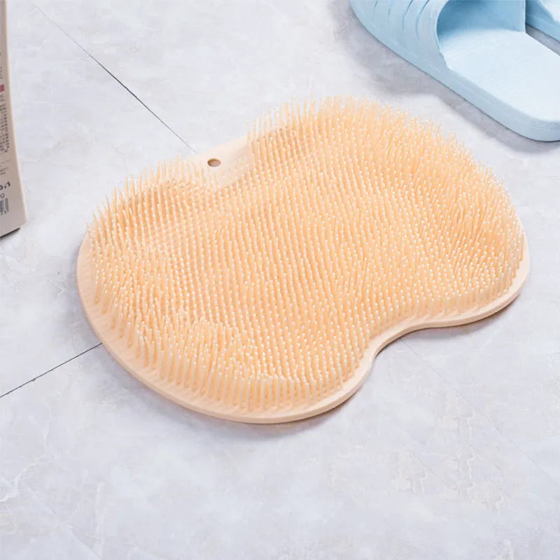 Orange silicone bristle bath brush with suction cup base on bathroom tiles.