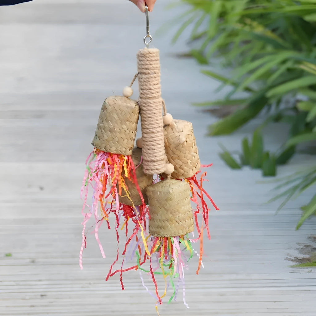 Colourful shredded paper parrot toy on wooden perch with sisal rope attachments