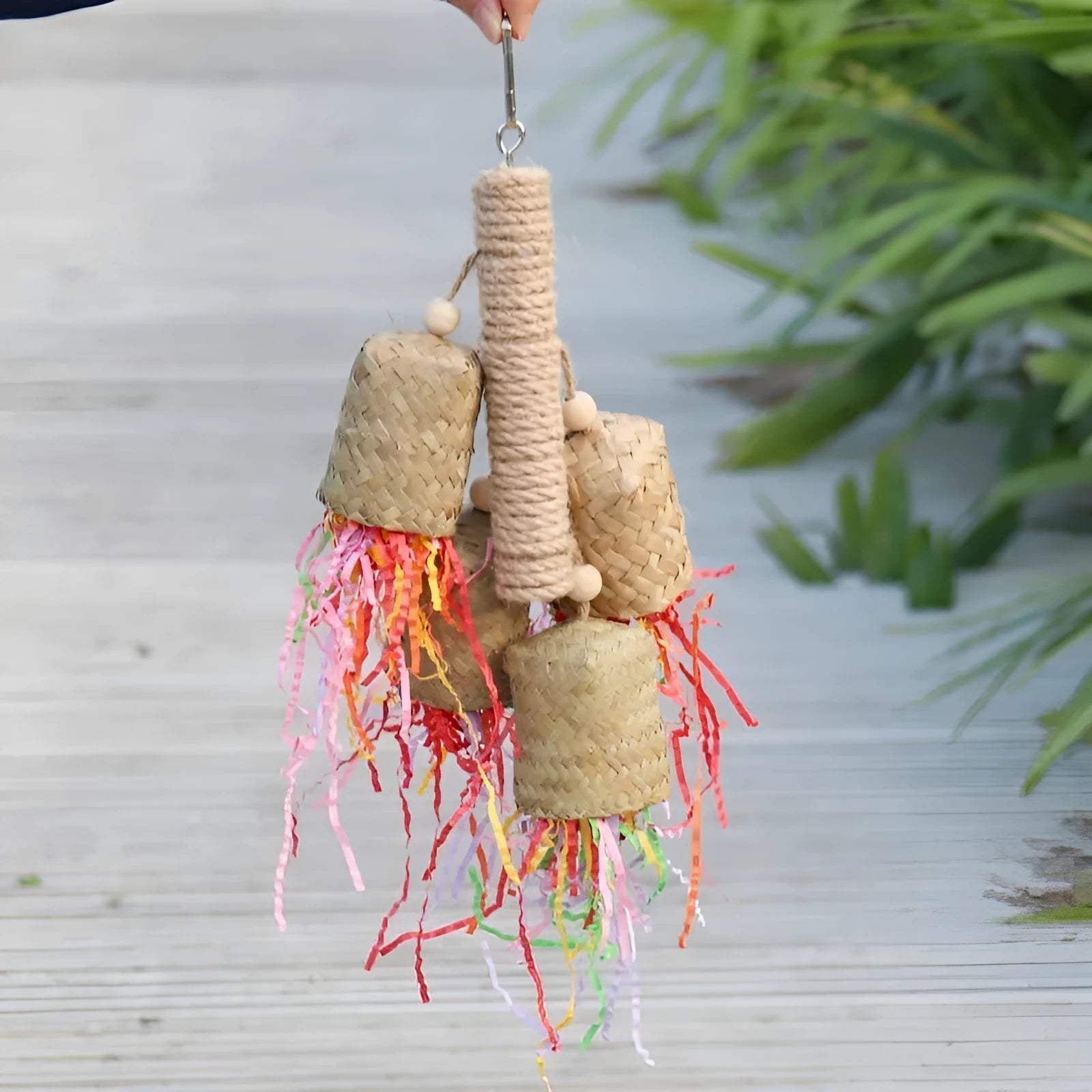 Colourful shredded paper parrot toy on wooden perch with sisal rope attachments