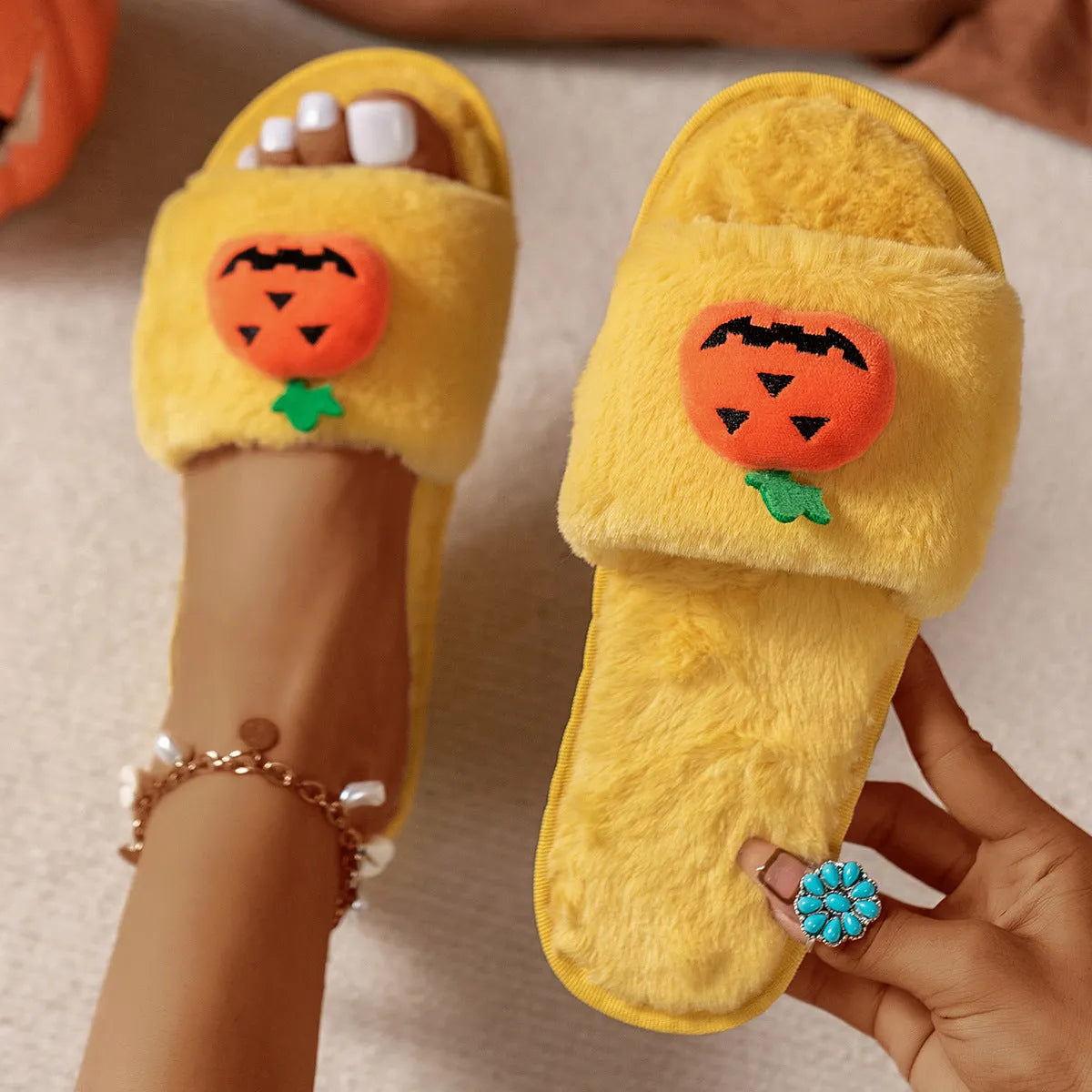 Halloween cartoon pumpkin design open-toe plush slippers on a white or yellow synthetic fur upper with PVC sole.