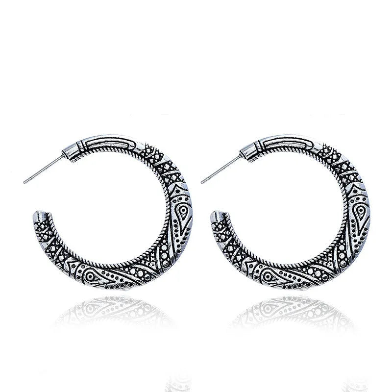 A pair of vintage-style C-shaped alloy earrings with an engraved surface, shown in bronze and silver colour options.