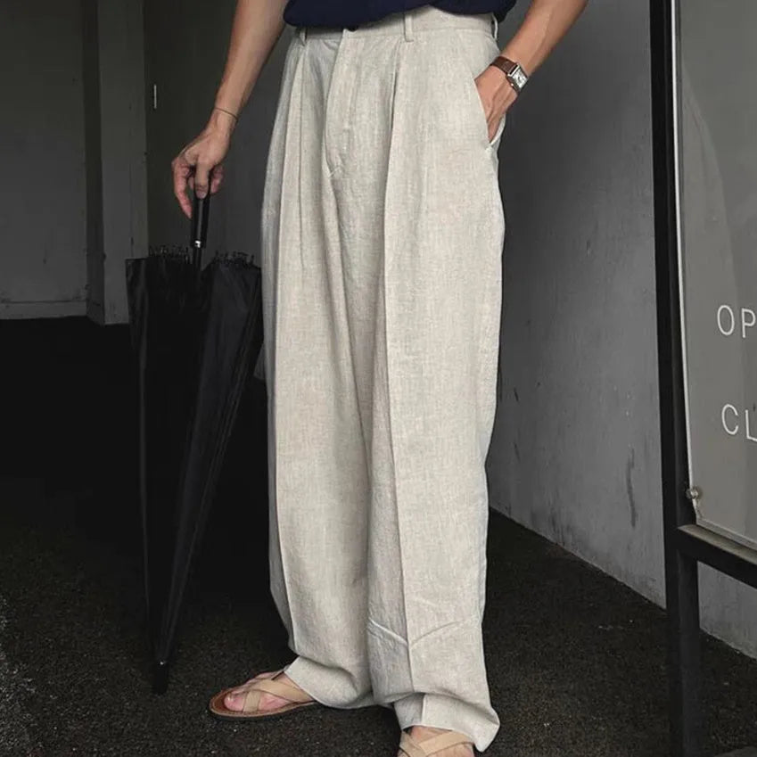Man wearing loose apricot wide-leg cotton linen blend trousers with a pencil-leg opening.