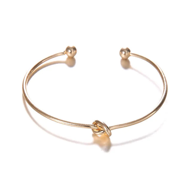 Gold women's cuff bracelet with arrow knot design on alloy electroplated band