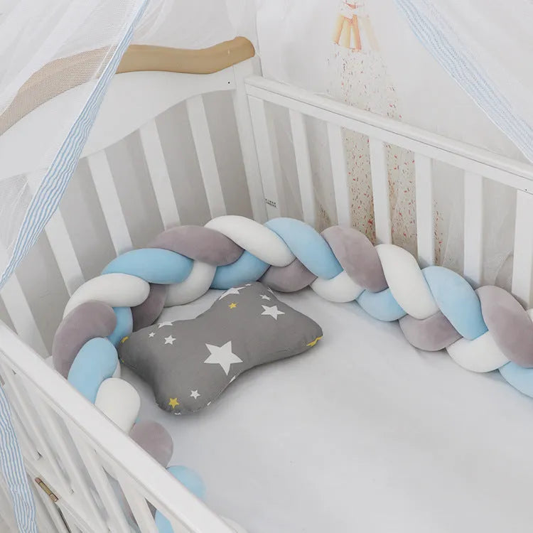 Braided knot design crib bumper in spandex velvet, shown in a light grey colour wrapped around crib slats.