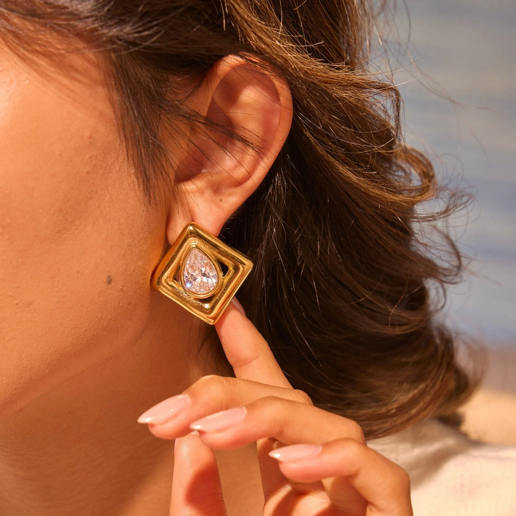 Geometric gold stud earrings with a water drop zircon stone inlaid in the centre.