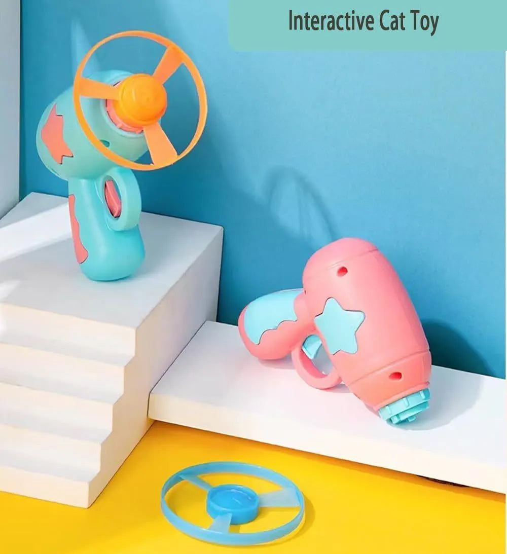 Blue plastic interactive cat toy gun with a mounted pink Frisbee on a table.