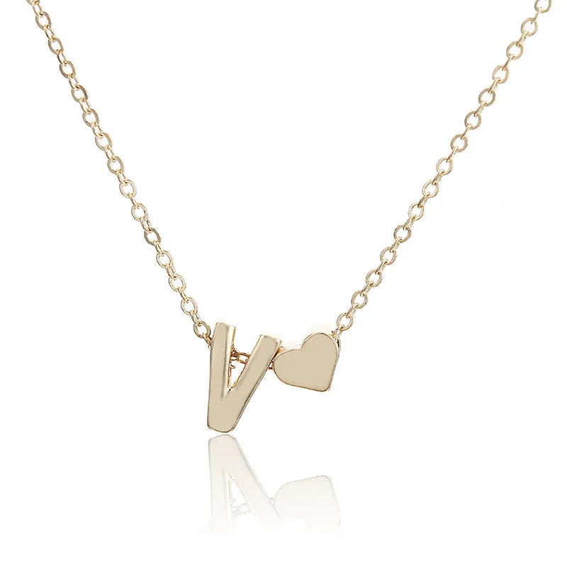 Gold heart shaped alloy pendant with initial letter on white background