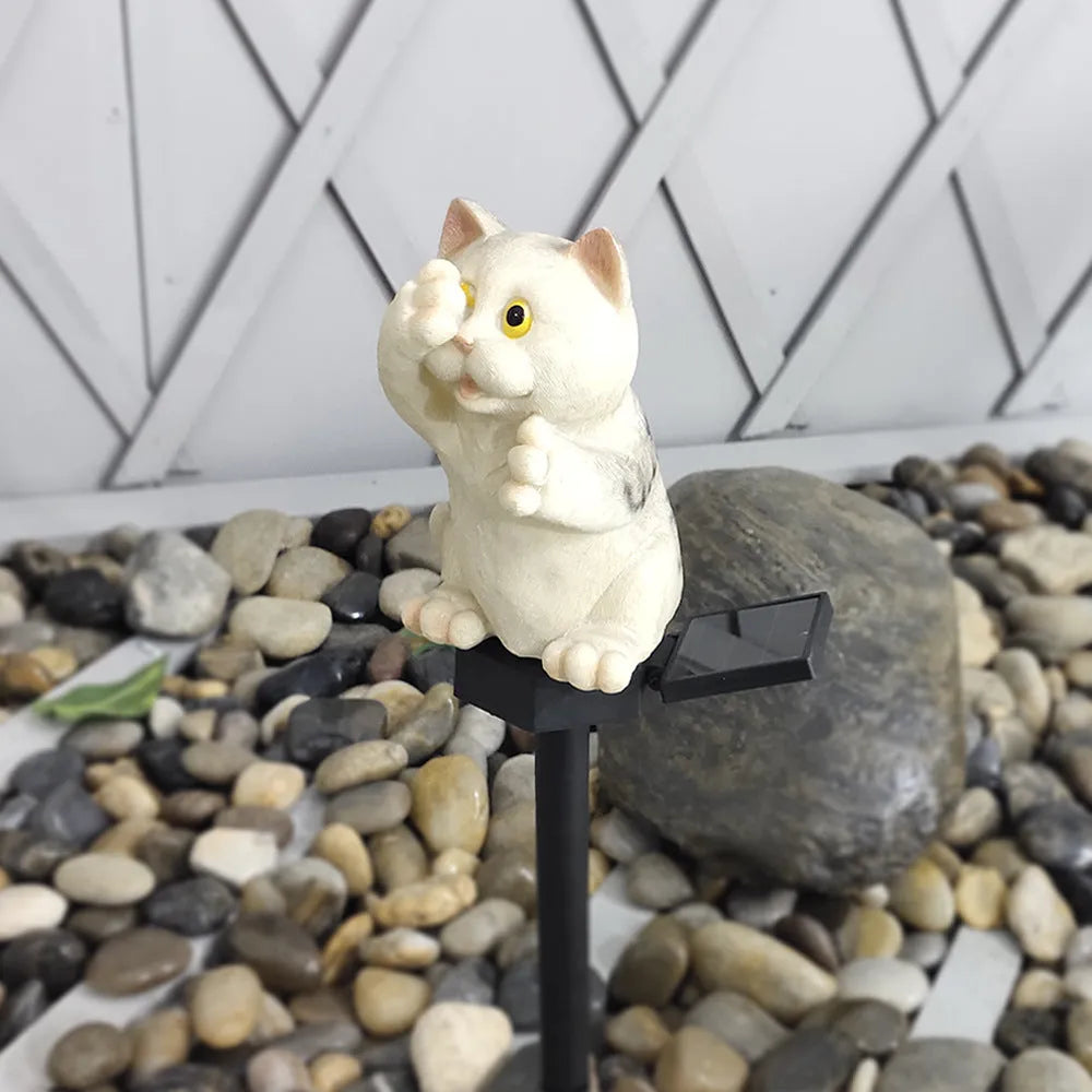 Brown resin cat-shaped solar garden light with LED on a lawn.