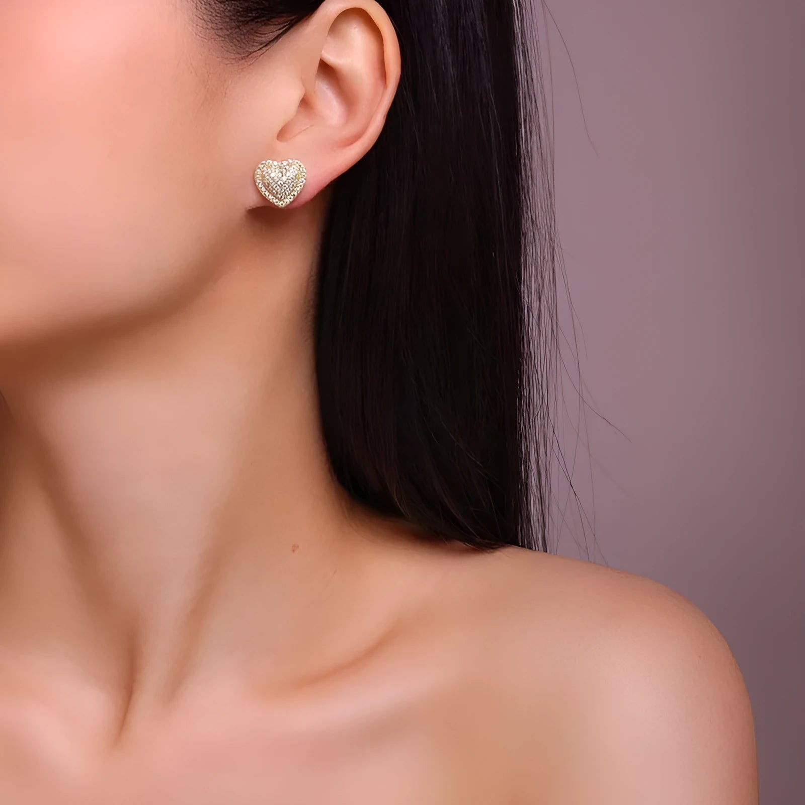 A pair of simple gold-tone heart-shaped stud earrings with a moissanite stone, shown from the front.