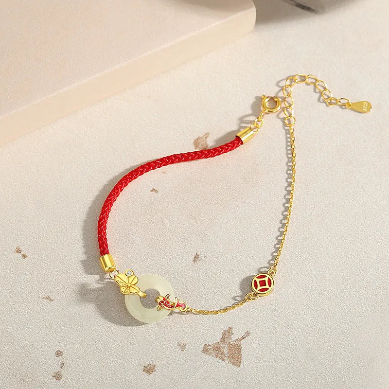Gold and red women's bracelet with a silver peace buckle, red rope, and Hetian jade charm.