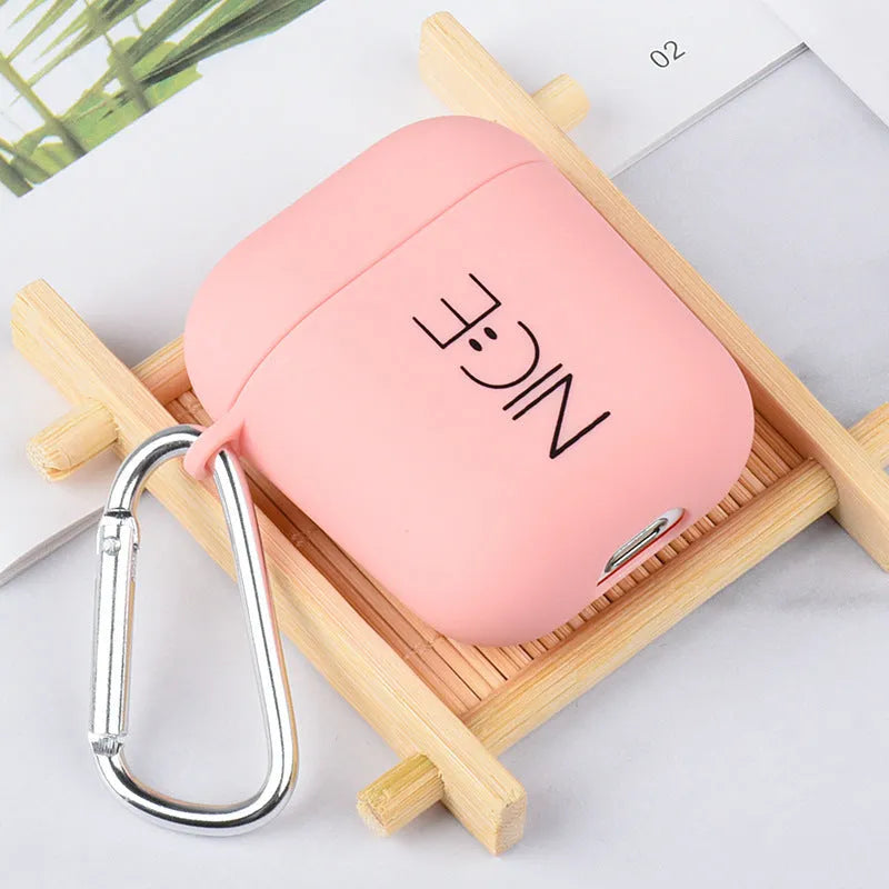 Black AirPods hard case with a smiley face design next to a pink case with a flower pattern.