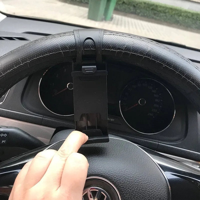 Black steering wheel phone mount holder clipped to a car wheel, holding a large smartphone.