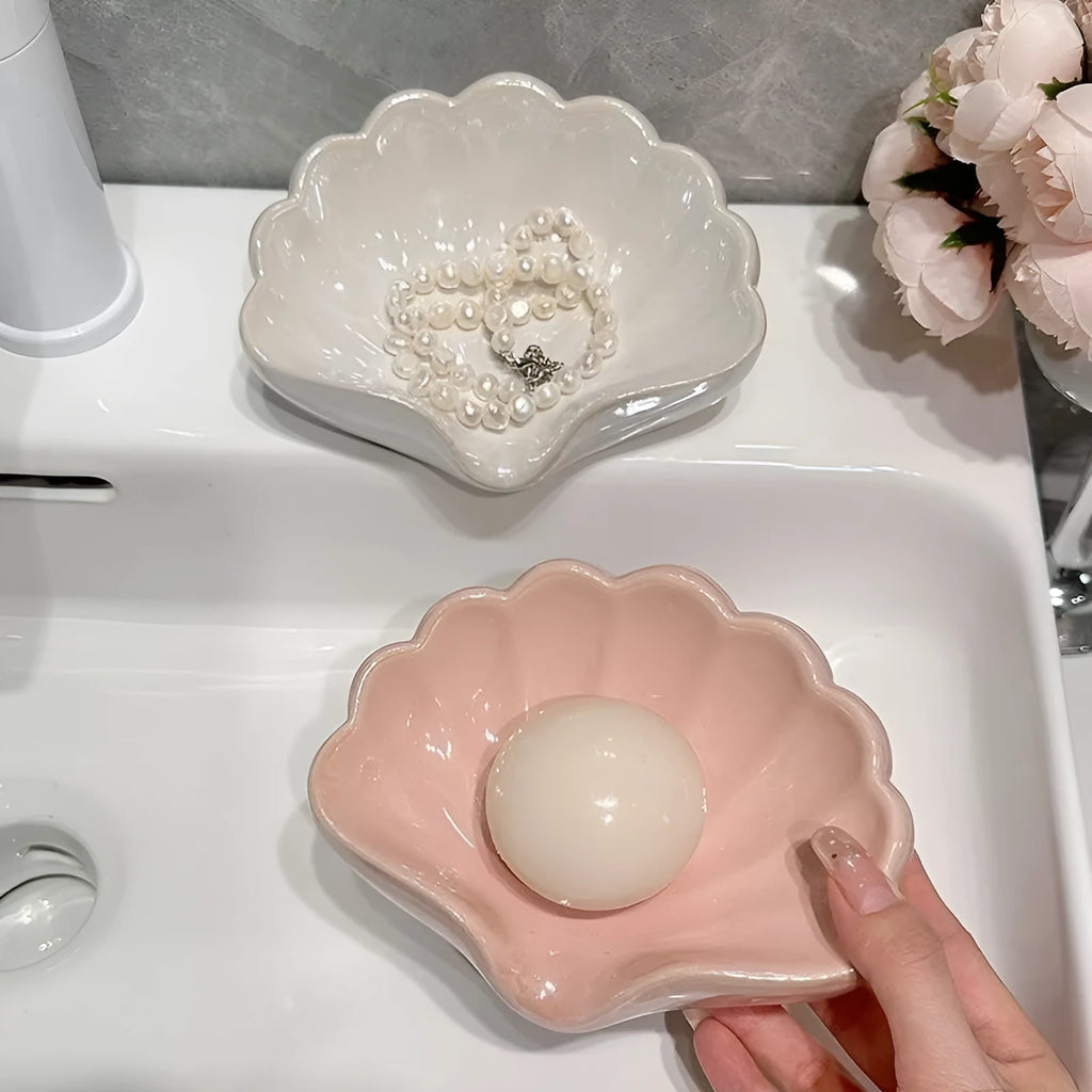 White shell-shaped plastic soap dish with drainage holes on a bathroom counter.