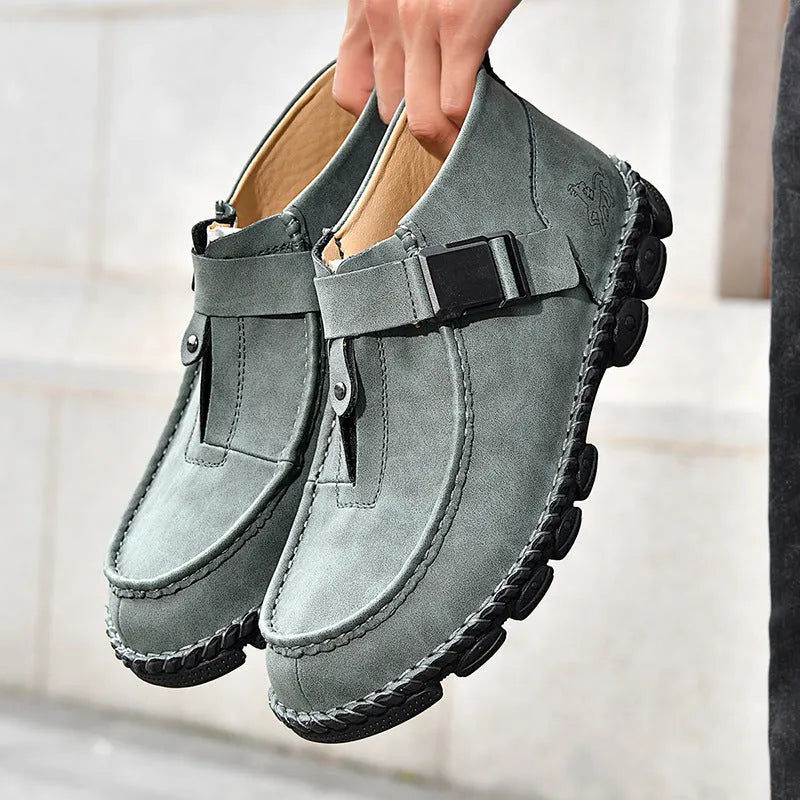 Men's black casual slip-on flat shoes with visible handmade stitching around the sole.