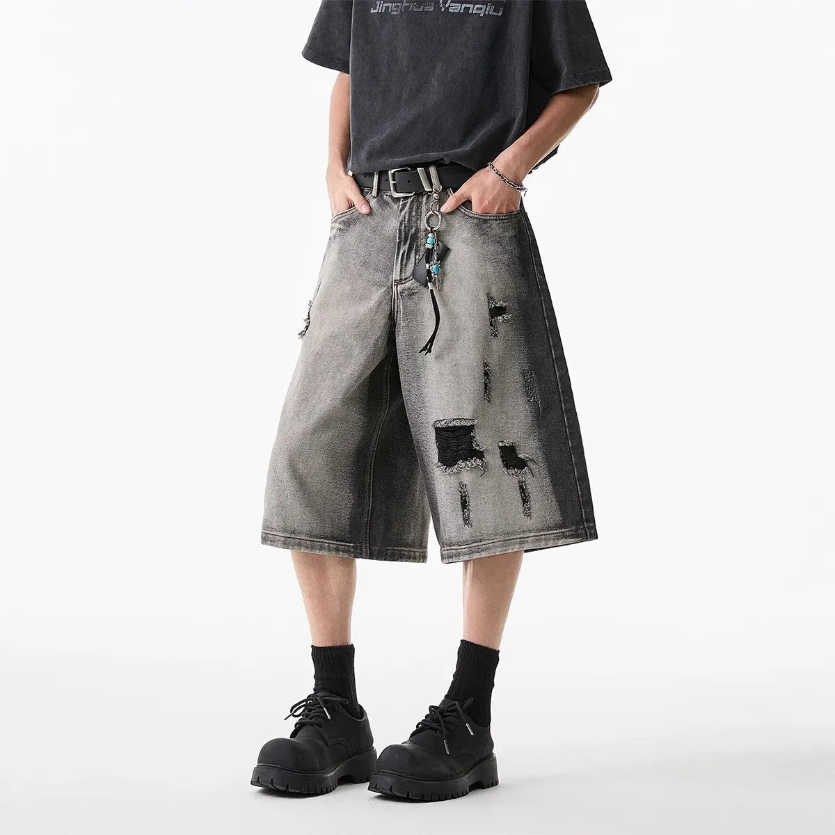 Grey loose fit denim shorts with distressed holes and a cropped length on a hanger.