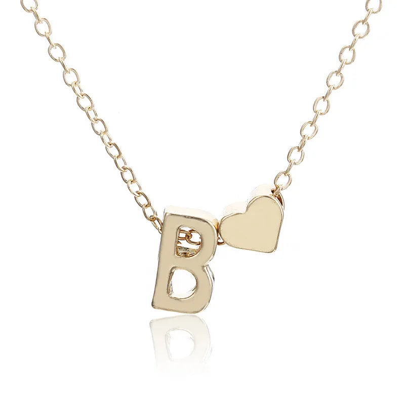 Gold heart shaped alloy pendant with initial letter on white background