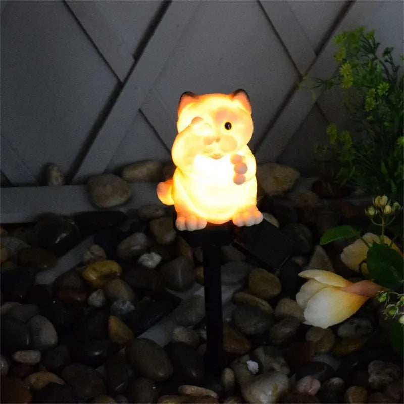 Brown resin cat-shaped solar garden light with LED on a lawn.